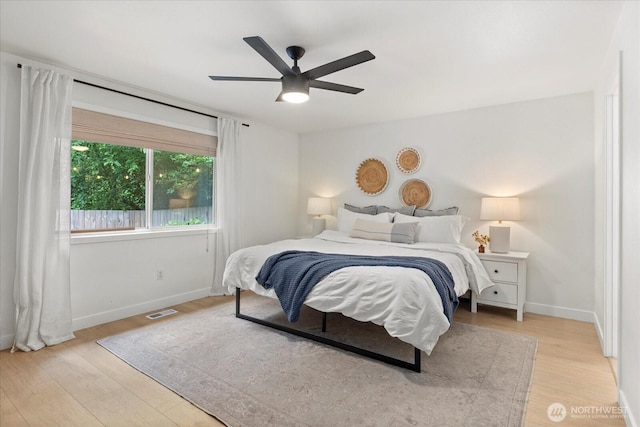 bedroom featuring light wood finished floors, baseboards, and a ceiling fan