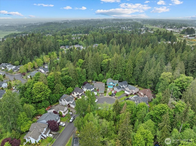 aerial view of property's location featuring a forest and nearby suburban area