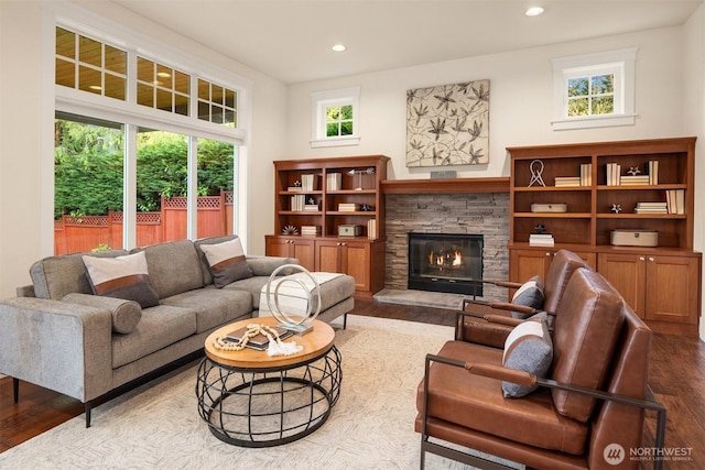 living room featuring wood finished floors, recessed lighting, and a stone fireplace