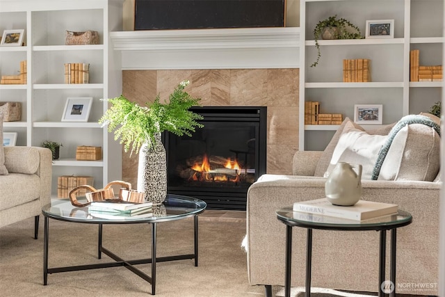living area featuring a fireplace, built in shelves, and carpet