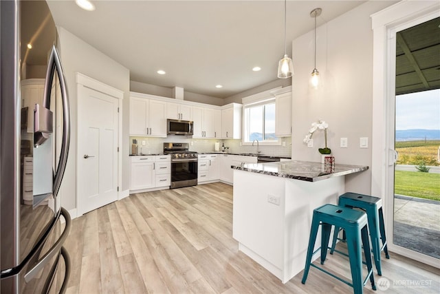 470 S Partridge Ln, East Wenatchee, WA 98802 - kitchen featuring stainless steel appliances, a peninsula, light wood-style flooring, decorative backsplash, and dark stone counters