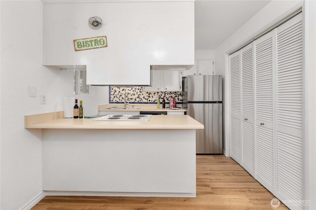 8309 Cirque Dr W Unit 4, University Place, WA 98467 - kitchen with freestanding refrigerator, a peninsula, light countertops, light wood-style flooring, and a sink