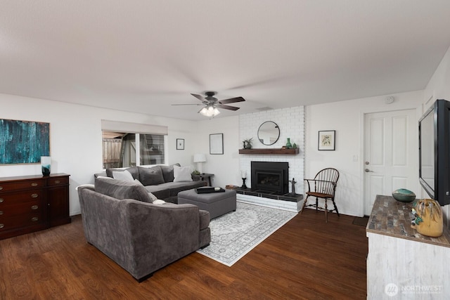 living area with dark wood-style floors, ceiling fan, and a fireplace