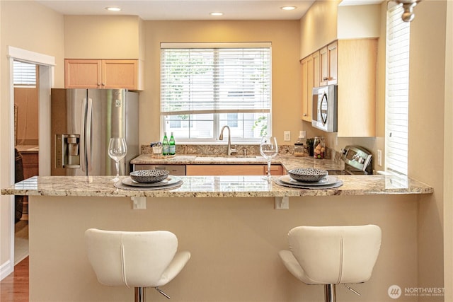 2050 132nd Ave SE Unit E-512, Bellevue, WA 98005 - kitchen with appliances with stainless steel finishes, a sink, light brown cabinets, a peninsula, and light stone counters