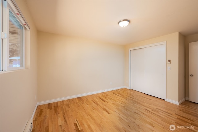 unfurnished bedroom featuring light wood-style floors, a closet, and baseboards