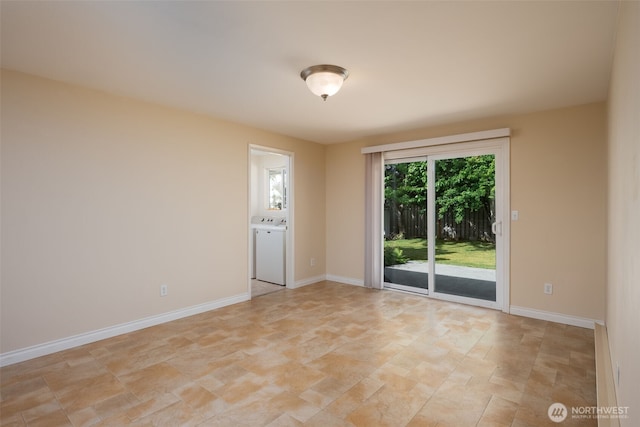 spare room featuring stone finish floors, washer / dryer, and baseboards