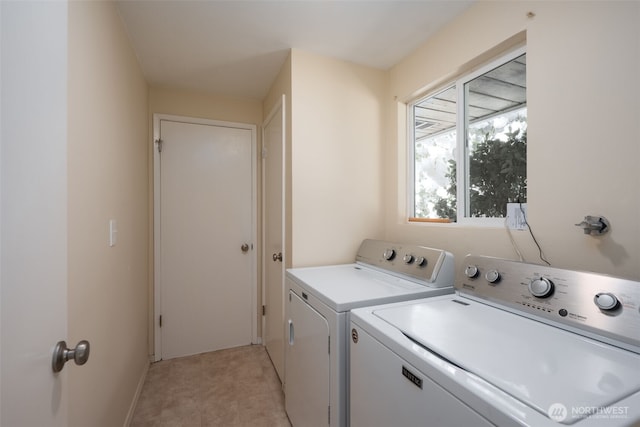 clothes washing area with separate washer and dryer and baseboards