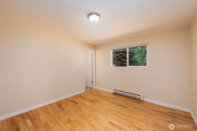 empty room featuring a baseboard radiator, light wood-style floors, and baseboards