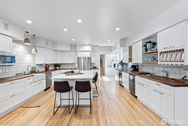 7340 Hawkstone Ave SW, Port Orchard, WA 98367 - kitchen with wooden counters, wine cooler, appliances with stainless steel finishes, a breakfast bar area, and tasteful backsplash