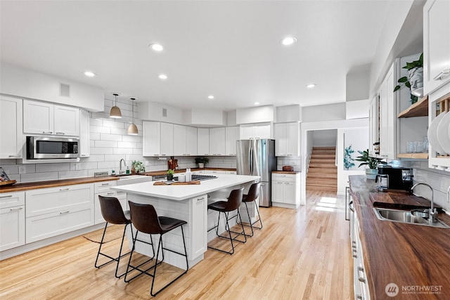 7340 Hawkstone Ave SW, Port Orchard, WA 98367 - kitchen with stainless steel appliances, wood counters, a sink, a breakfast bar area, and tasteful backsplash