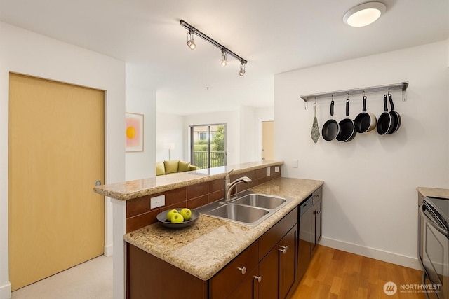 kitchen featuring a sink, a peninsula, range with electric stovetop, baseboards, and light countertops