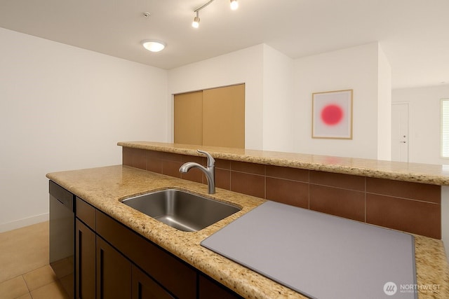 kitchen featuring a sink, dishwasher, light stone counters, baseboards, and dark brown cabinets
