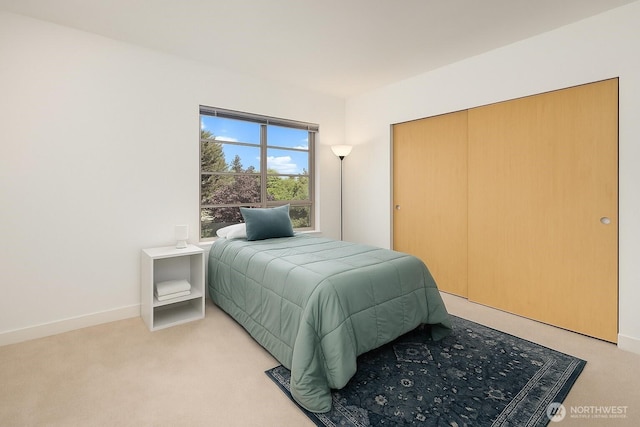 bedroom with light carpet, baseboards, and a closet