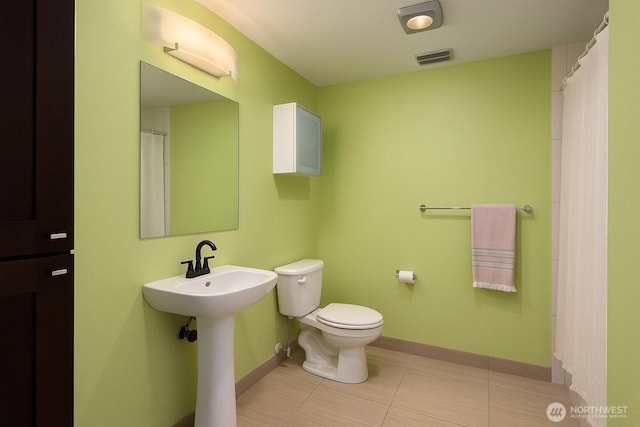 bathroom with toilet, baseboards, tile patterned floors, and a sink
