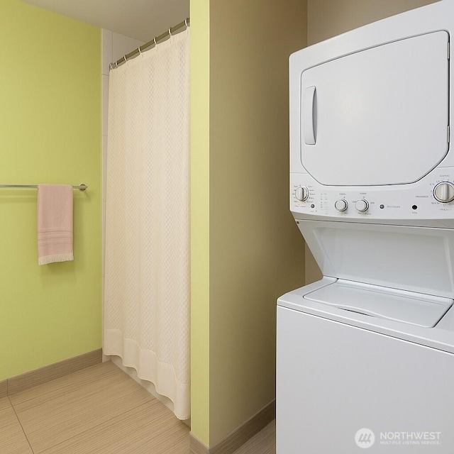 washroom with stacked washing machine and dryer and baseboards