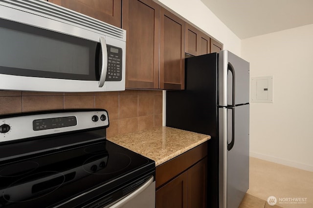 kitchen featuring stainless steel appliances, decorative backsplash, light stone counters, dark brown cabinets, and baseboards