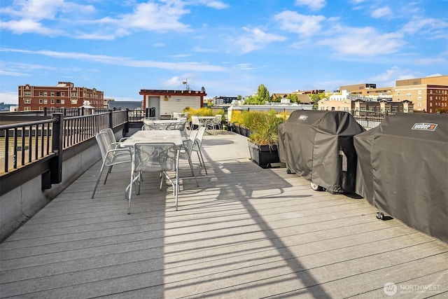 wooden deck with outdoor dining space and area for grilling