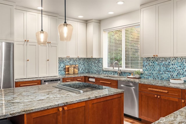 kitchen featuring appliances with stainless steel finishes, a sink, light stone counters, tasteful backsplash, and white cabinetry