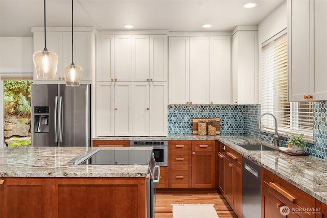 kitchen with appliances with stainless steel finishes, a sink, light wood-style flooring, white cabinets, and recessed lighting