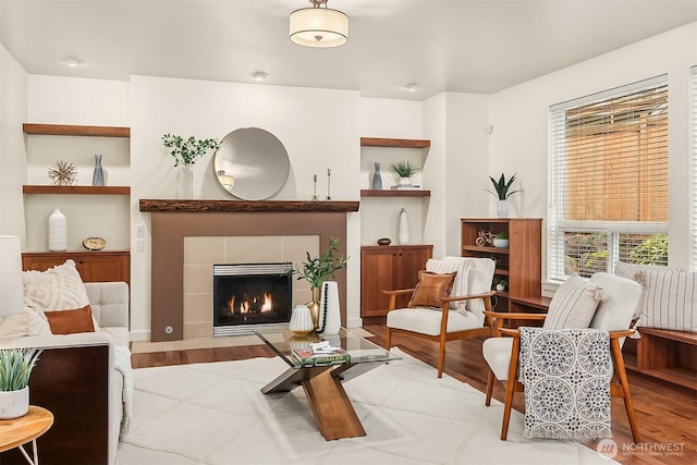 sitting room with a fireplace, built in features, and wood finished floors