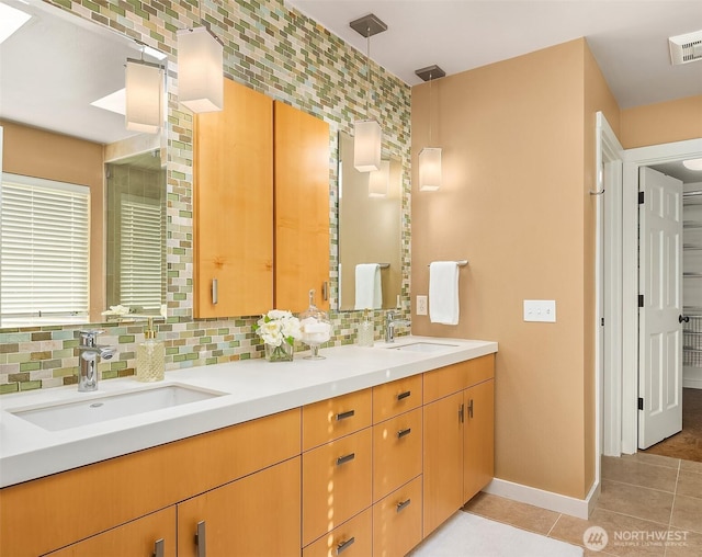 full bath featuring tile patterned flooring, decorative backsplash, double vanity, and baseboards