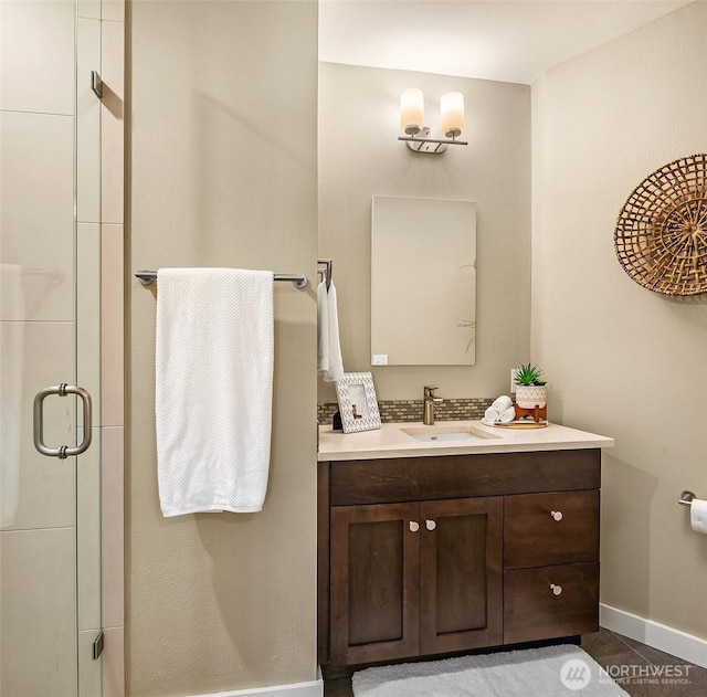 full bathroom with vanity, a stall shower, baseboards, and tile patterned floors