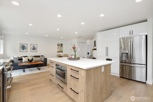 kitchen featuring appliances with stainless steel finishes, modern cabinets, light wood-style flooring, light brown cabinets, and a kitchen island