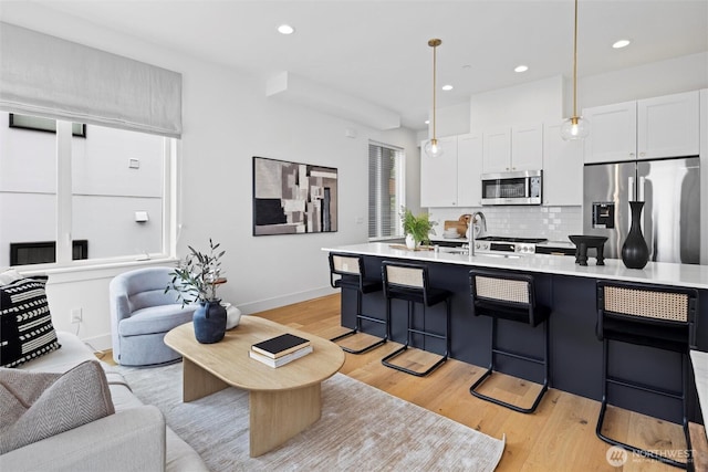 kitchen with appliances with stainless steel finishes, open floor plan, light wood-style flooring, light countertops, and recessed lighting