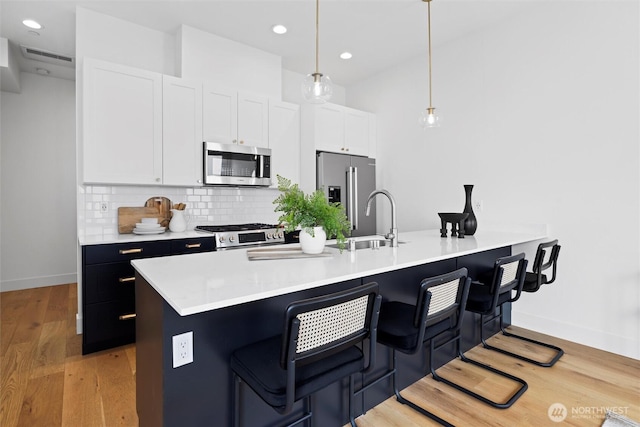 kitchen featuring stainless steel appliances, a breakfast bar area, baseboards, tasteful backsplash, and a peninsula