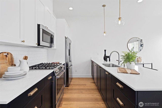kitchen with appliances with stainless steel finishes, a sink, backsplash, white cabinetry, and a peninsula