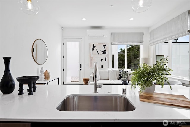 kitchen featuring a sink, plenty of natural light, a wall unit AC, recessed lighting, and decorative light fixtures