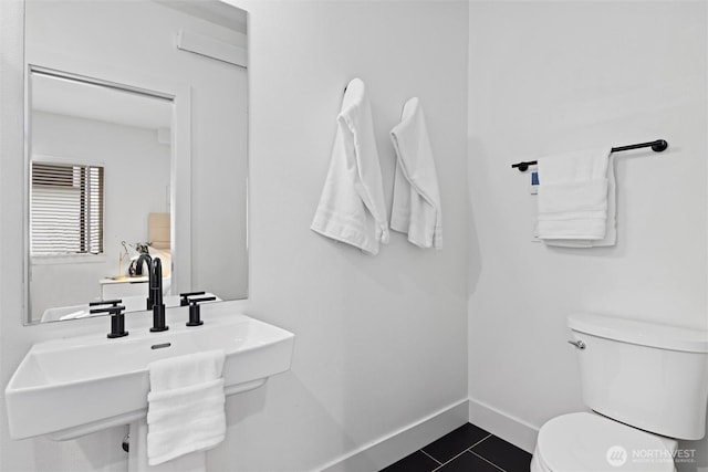 bathroom with toilet, a sink, tile patterned flooring, and baseboards