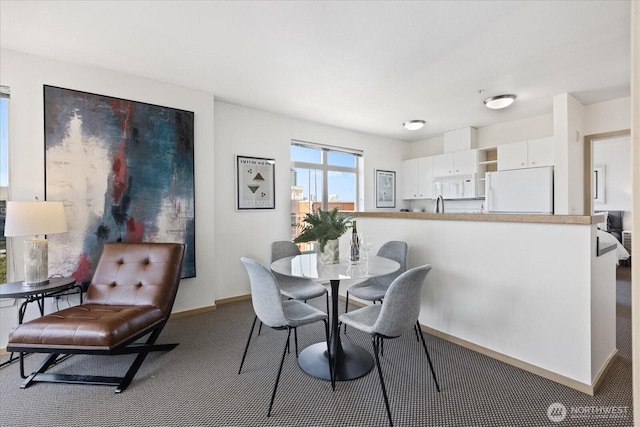 carpeted dining space with baseboards