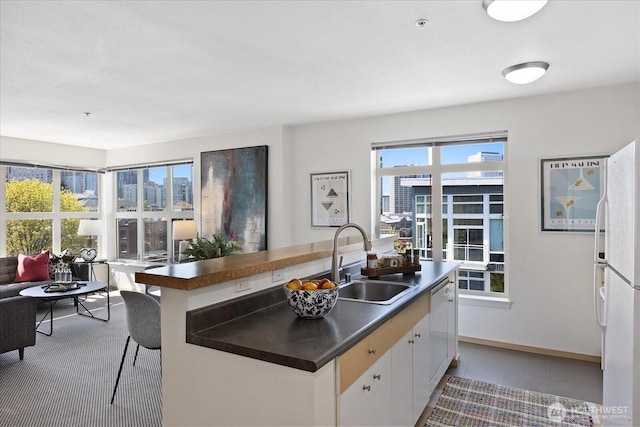 kitchen featuring a sink, white appliances, dark countertops, white cabinetry, and tile patterned floors
