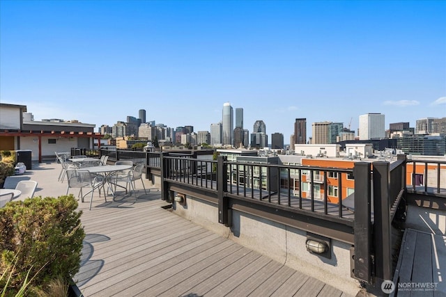 wooden terrace featuring a skyline view and outdoor dining area