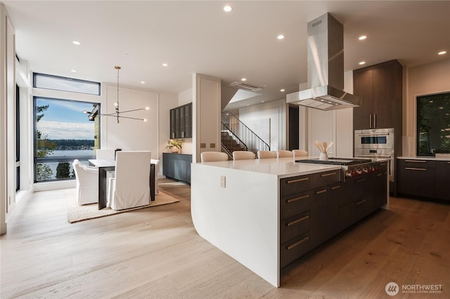 7128 NE 119th Ln, Kirkland, WA 98034 - kitchen with island exhaust hood, modern cabinets, stainless steel appliances, light wood-style flooring, and a chandelier