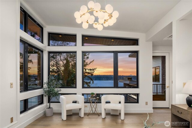 7128 NE 119th Ln, Kirkland, WA 98034 - dining room featuring wood finished floors, a chandelier, baseboards, and a water view