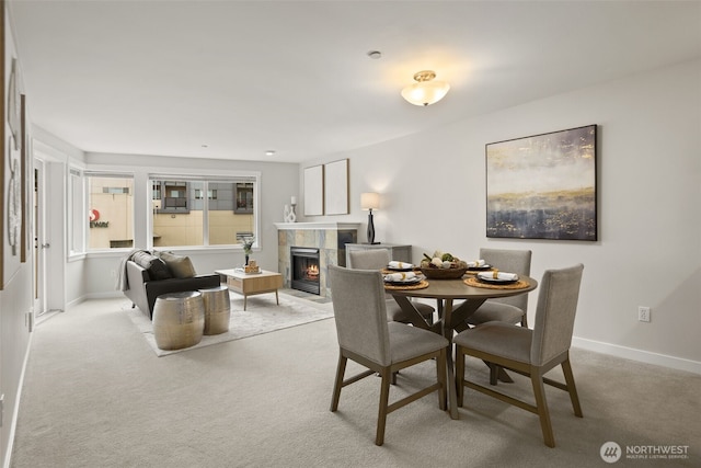 dining space with a tiled fireplace, carpet floors, and baseboards
