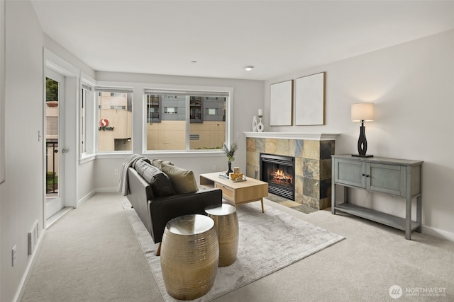 carpeted living room featuring a tiled fireplace and baseboards