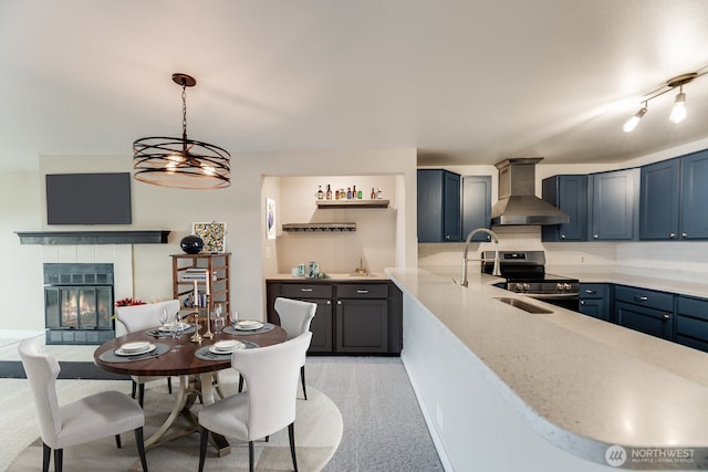 965 W Nickerson St Unit 33, Seattle, WA 98119 - kitchen featuring wall chimney exhaust hood, stainless steel electric range, a tile fireplace, hanging light fixtures, and backsplash