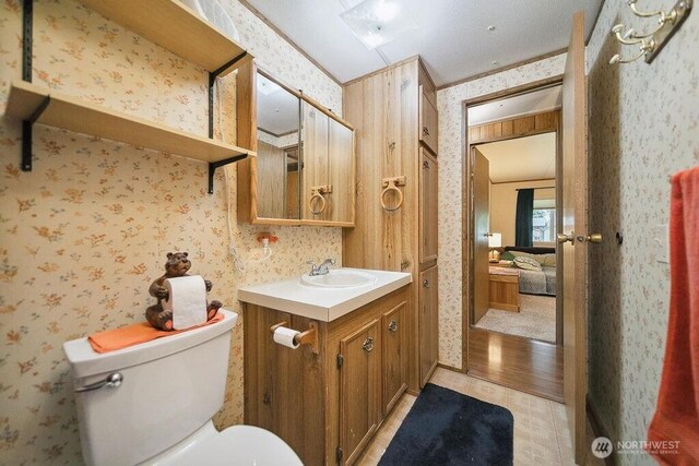 17465 NE Noll Rd NE, Poulsbo, WA 98370 - bathroom featuring wallpapered walls, toilet, vanity, and wood finished floors