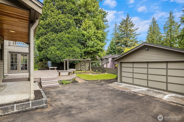exterior space featuring french doors, an outbuilding, fence, a deck, and a detached garage