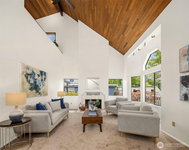 carpeted living room with wood ceiling, high vaulted ceiling, a brick fireplace, baseboards, and beamed ceiling