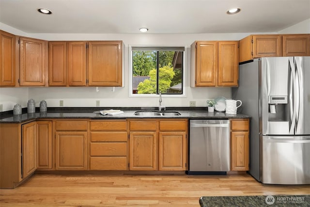kitchen with stainless steel appliances, a sink, light wood finished floors, brown cabinets, and recessed lighting