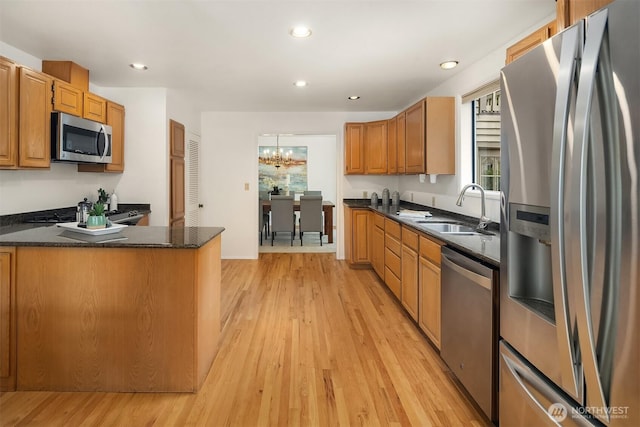 kitchen with stainless steel appliances, a sink, light wood-style floors, a chandelier, and recessed lighting