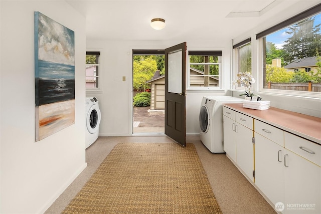 clothes washing area with cabinet space and baseboards