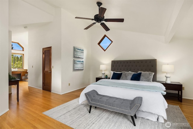 bedroom with high vaulted ceiling, light wood-style flooring, baseboards, and a ceiling fan