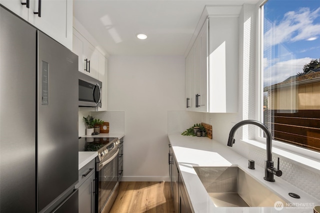 kitchen featuring appliances with stainless steel finishes, a sink, tasteful backsplash, light countertops, and recessed lighting