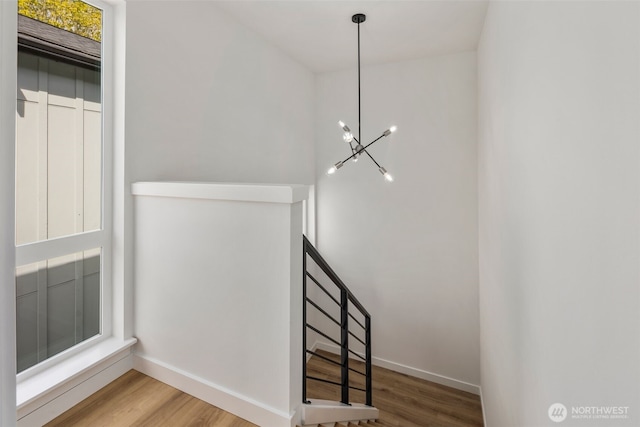 stairs with wood finished floors, a chandelier, and baseboards