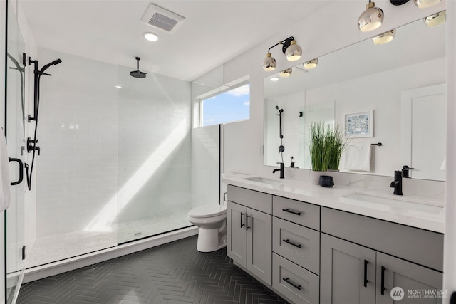 bathroom with a shower stall, double vanity, and toilet